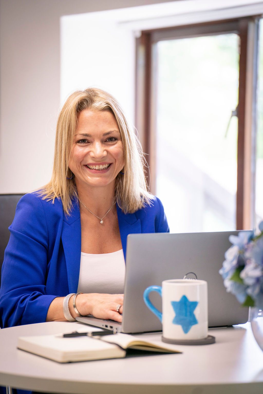 Charley Southon at her laptop, notebook and mug on the table in front of her